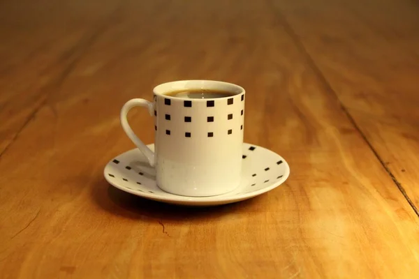 木製の背景にソーサー上の完全なコーヒーカップのビュー — ストック写真