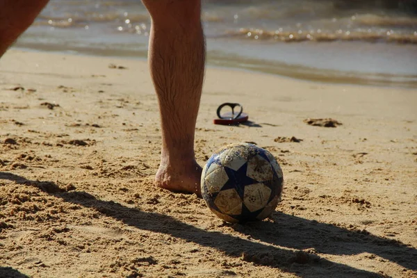 Kumsalda futbol oynayan insanların bacaklarına bakın. 