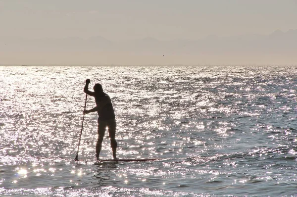 Denizdeki bir sörfçünün güneş ışığındaki siluetin görüntüsü