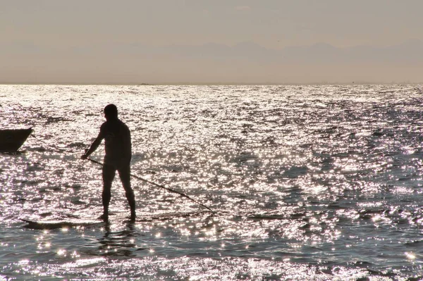 Denizdeki bir sörfçünün güneş ışığındaki siluetin görüntüsü
