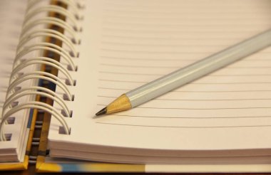 Kahverengi tahta masa zemininde beyaz defter kalemi