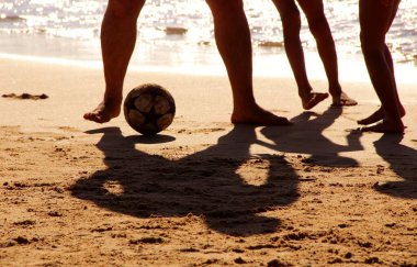Kumsalda futbol oynayan insanların bacaklarına bakın. 
