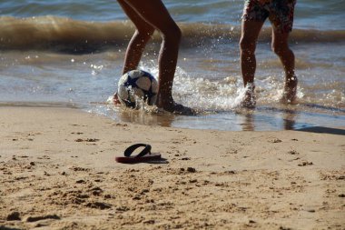 Kumsalda futbol oynayan insanların bacaklarına bakın. 