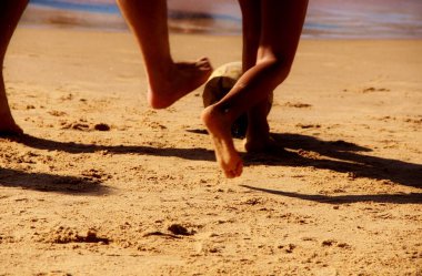 Kumsalda futbol oynayan insanların bacaklarına bakın. 