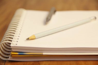 Kahverengi tahta masa zemininde kalem ve kalemle beyaz defter