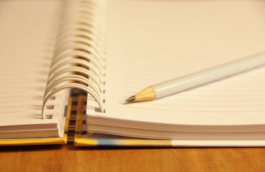 Kahverengi tahta masa zemininde beyaz defter kalemi