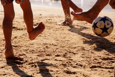 Kumsalda futbol oynayan insanların bacaklarına bakın. 