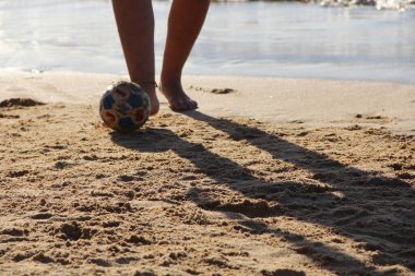 Kumsalda futbol oynayan insanların bacaklarına bakın. 