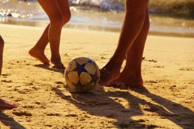 Kumsalda futbol oynayan insanların bacaklarına bakın. 