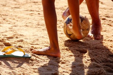 Kumsalda futbol oynayan insanların bacaklarına bakın. 