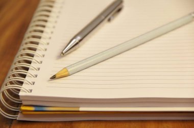 Kahverengi tahta masa zemininde kalem ve kalemle beyaz defter