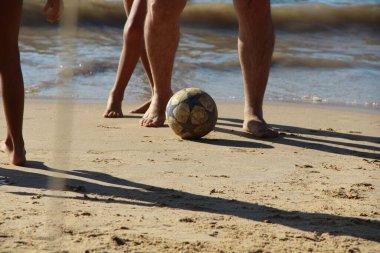 Kumsalda futbol oynayan insanların bacaklarına bakın. 