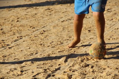Kumsalda futbol oynayan insanların bacaklarına bakın. 