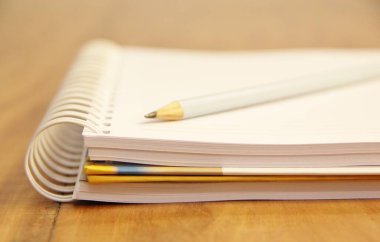 Kahverengi ahşap masa zemininde kurşun kalemli beyaz defter