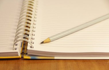 Kahverengi tahta masa zemininde beyaz defter kalemi