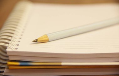 Kahverengi ahşap masa zemininde kurşun kalemli beyaz defter