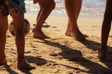 Kumsalda futbol oynayan insanların bacaklarına bakın. 