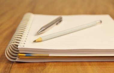 Kahverengi tahta masa zemininde kalem ve kalemle beyaz defter