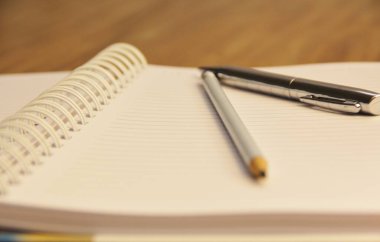 Kahverengi tahta masa zemininde kalem ve kalemle beyaz defter