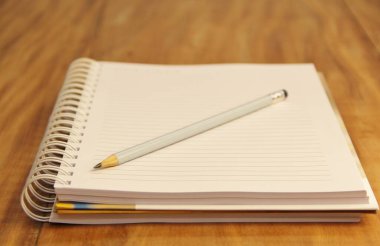 Kahverengi ahşap masa zemininde kurşun kalemli beyaz defter