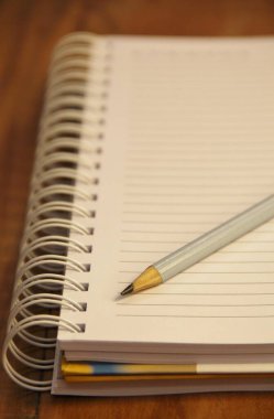 Kahverengi ahşap masa zemininde kurşun kalemli beyaz defter