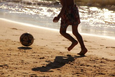 Kumsalda futbol oynayan insanların bacaklarına bakın. 