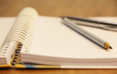 Kahverengi tahta masa zemininde kalem ve kalemle beyaz defter