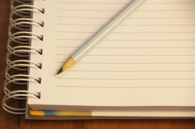 Kahverengi ahşap masa zemininde kurşun kalemli beyaz defter