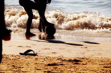 Kumsalda futbol oynayan insanların bacaklarına bakın. 