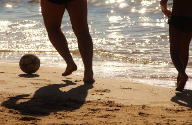 Kumsalda futbol oynayan insanların bacaklarına bakın. 