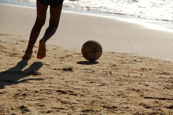 Kumsalda futbol oynayan insanların bacaklarına bakın. 