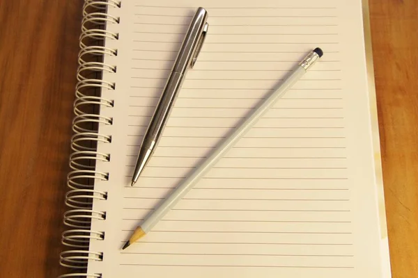 白いノートとペンと鉛筆の茶色の木製のテーブルの背景 — ストック写真