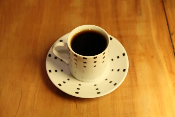 木製の背景にソーサー上の完全なコーヒーカップのビュー — ストック写真