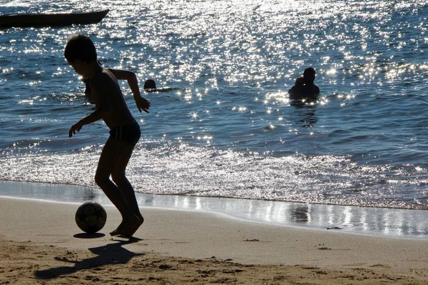 Futbol oynayan, yüzen ve kumsalda dinlenen insanları izleyin. 