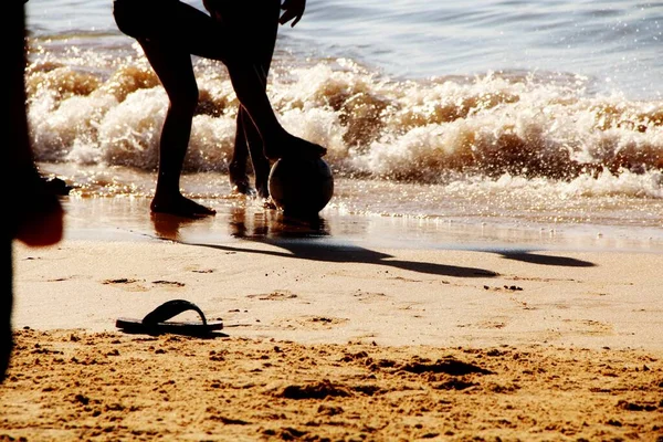 Kumsalda futbol oynayan insanların bacaklarına bakın. 