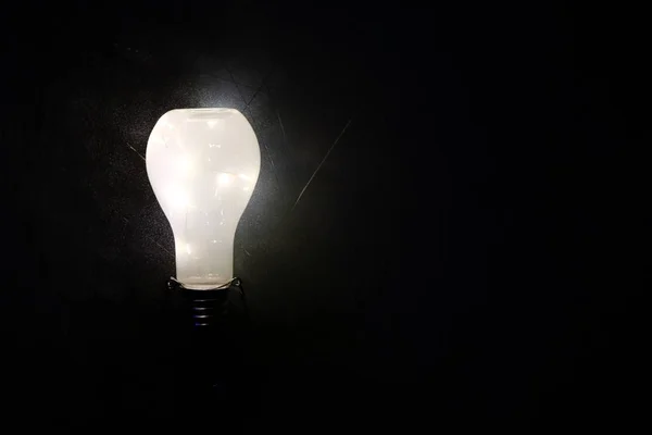 Glowing lightbulb on black background — Stock Photo, Image