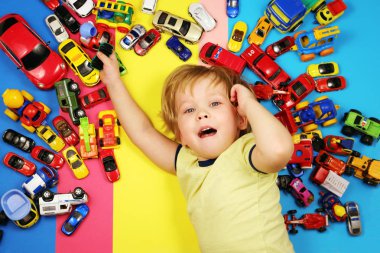 Oyuncak arabalar tarafından çevrili çok renkli arka plan üzerinde erkek bebek