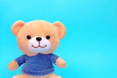 Çizgili süveter giyen oyuncak ayı mavi arka planda fotokopi alanı ile izole edildi