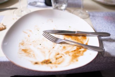 Öğle yemeğinden sonra çatal bıçak takımı ve yemek artıkları ile plaka