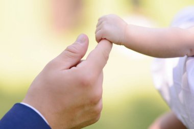 Bir bebeğin elini tutan genç bir çiftin elleri