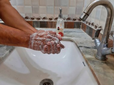 Elleri sabunla yıkayan birinin resmi.