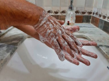 Elleri sabunla yıkayan birinin resmi.