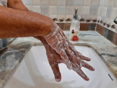 Elleri sabunla yıkayan birinin resmi.
