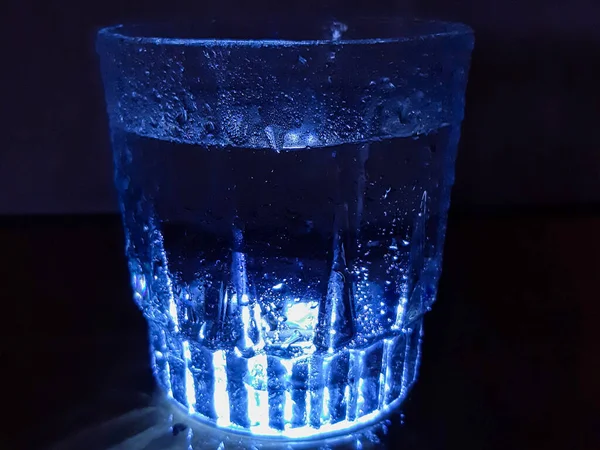 Bild Eines Beleuchteten Wasserglases Mit Wassertropfen Darüber Aufgenommen Vor Dunklem — Stockfoto