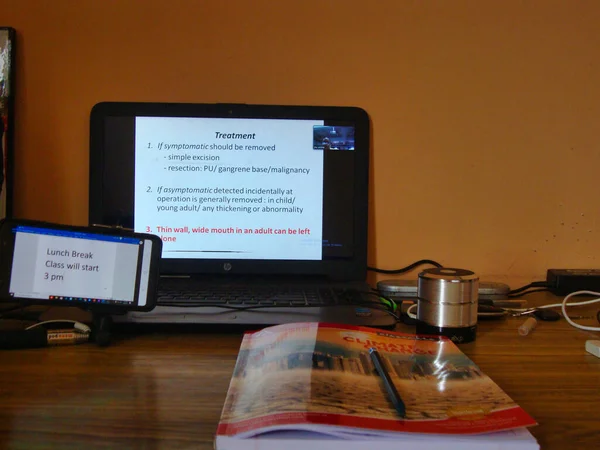 Jaipur, India-Circa 2020: Laptop 'un fotoğrafı, cep telefonu ve masanın üzerinde tutulan bir defter. Öğrenciler şu anda korona virüsü salgınıyla ilgili online dersler alıyorlar.