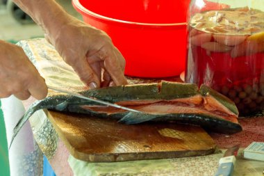 A man is cutting fresh fish at a ranch. Barbecue from pink salmon. Nutrition, food. clipart
