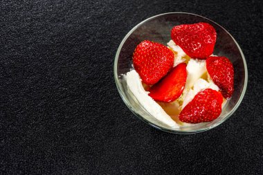 Siyah arka planda duran cam vazoda dondurmalı taze çilekler. Uzayı kopyala Üst görünüm