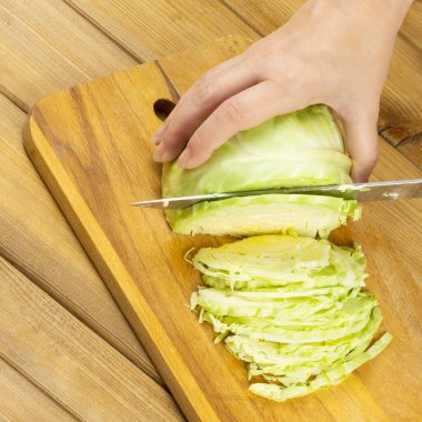 Kadınlar salata ya da borç hazırlamak için kesme tahtasıyla lahana kesiyorlar. Sağlıklı vejetaryen yemekleri. Ahşap arkaplan.