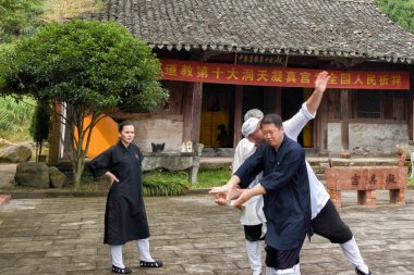 Zhejiang, China - October 17, 2016: Master (Shifu) teaches his students the basics of Wushu art in the Taoist Ningzhengong Monastery. Wudangpai is a school of traditional Wudang Wushu and Qigong clipart
