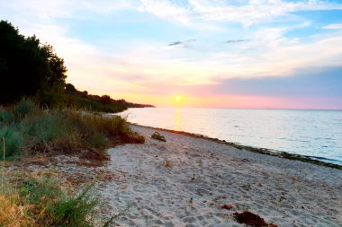 Açık renkli günbatımı, deniz yüzeyinde sarı güneş.